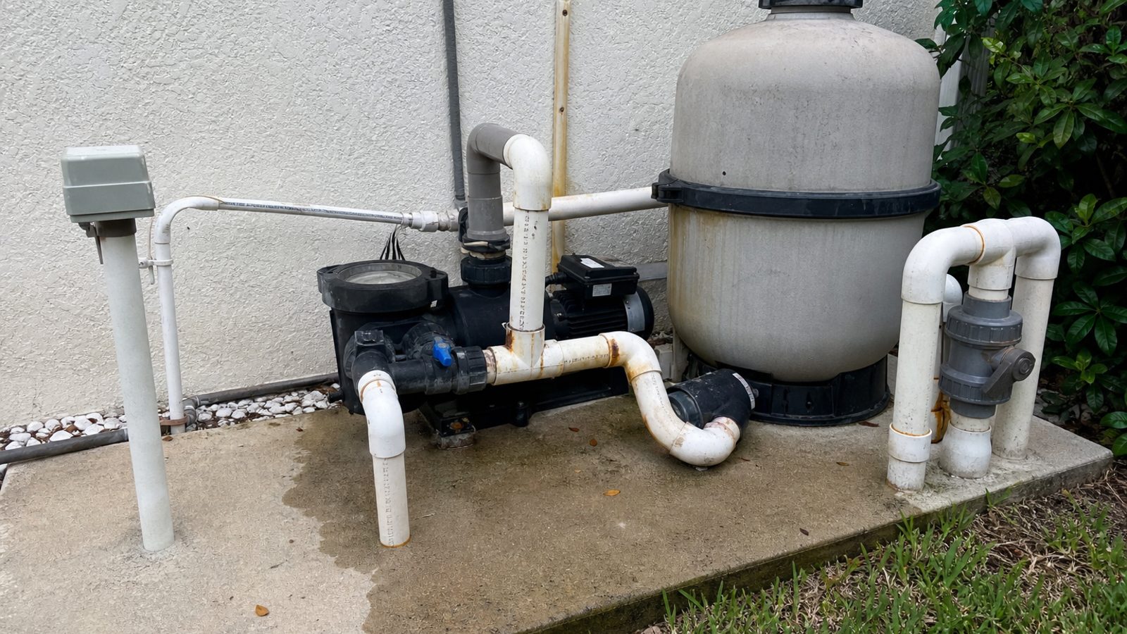 Florida pool equipment pad with pump and filter, slight rust stains at PVC joints, water mark on concrete
