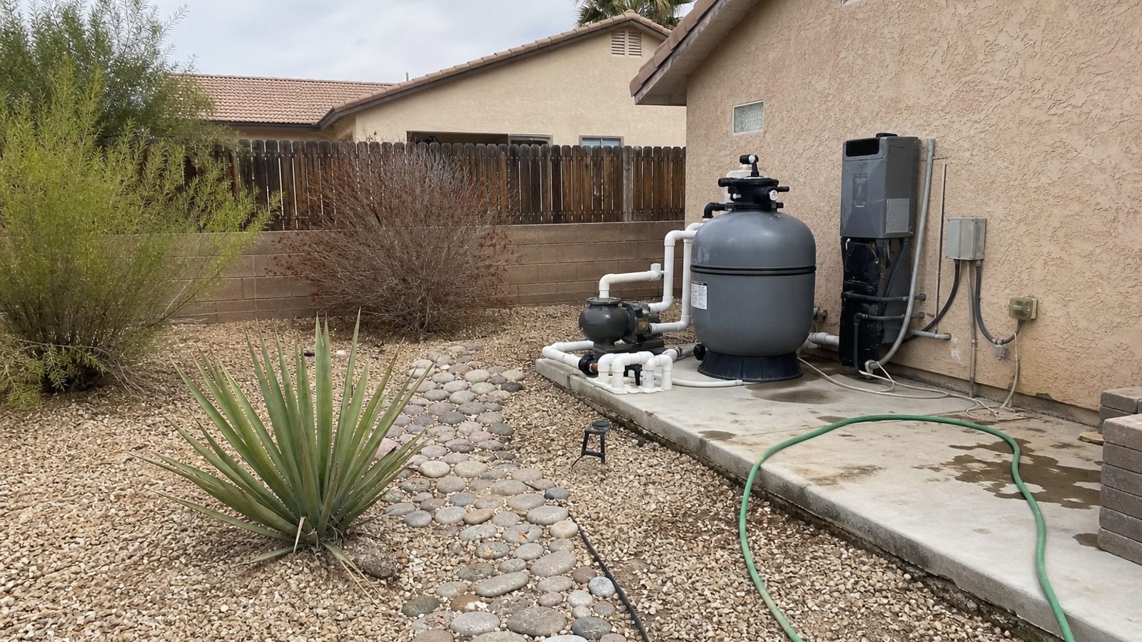 Nevada residential yard with pool equipment, dry landscaping, and sun-faded exterior materials
